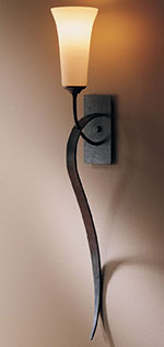 A Hubbardton Forge sweeping taper wall sconce in a hallway | Capitol Lighting