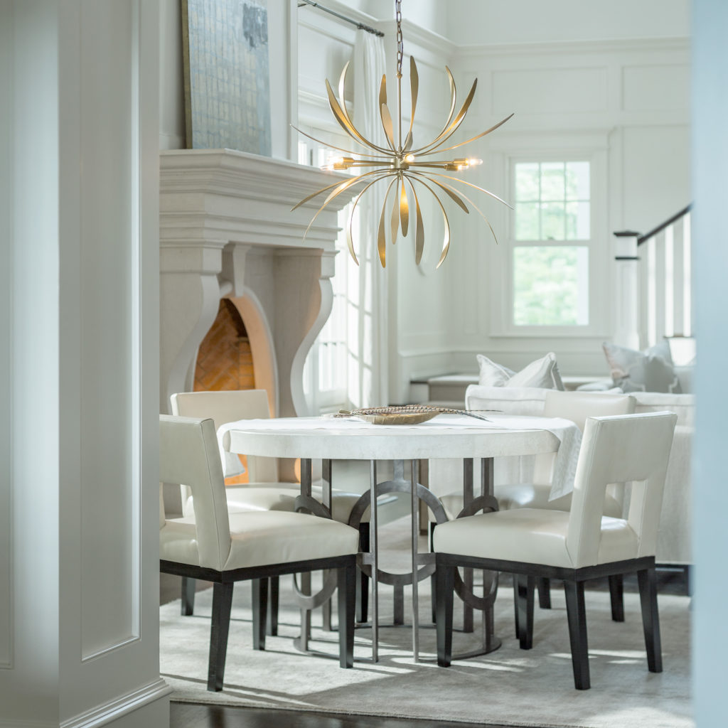 The Dahlia 32-Inch Chandelier is a blooming flower over a white modern dining table and chairs
