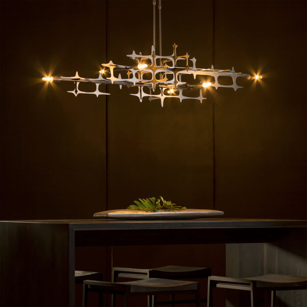 The contemporary Grid Pendant by Hubbardton Forge shines bright over a sleek, high-top dining table