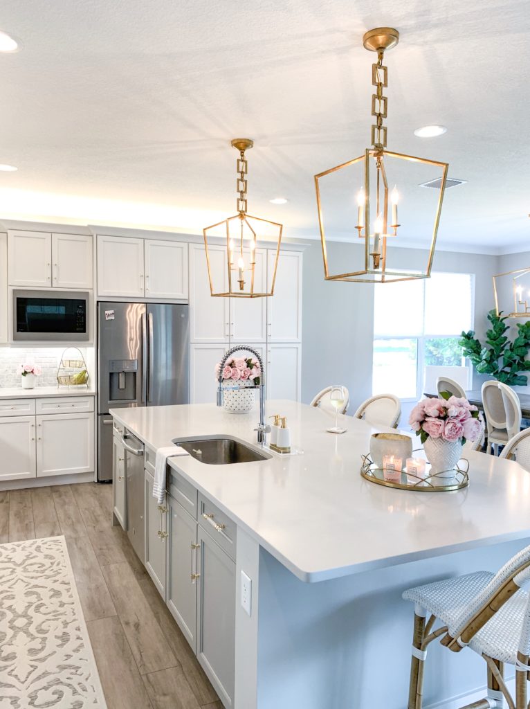 Two strikingly gold Urban Classic Denmark Pendants hang over a large, white kitchen island