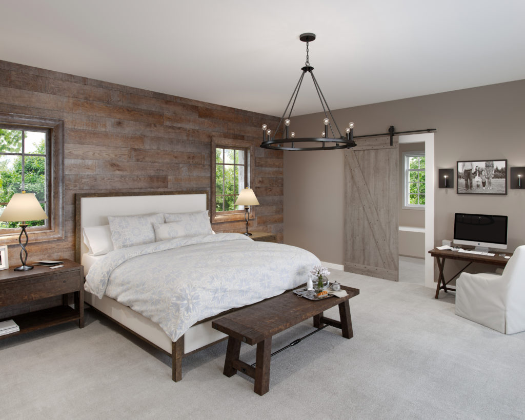A wrought-iron chandelier over a bed in a bedroom with a barn door and wooden accent wall