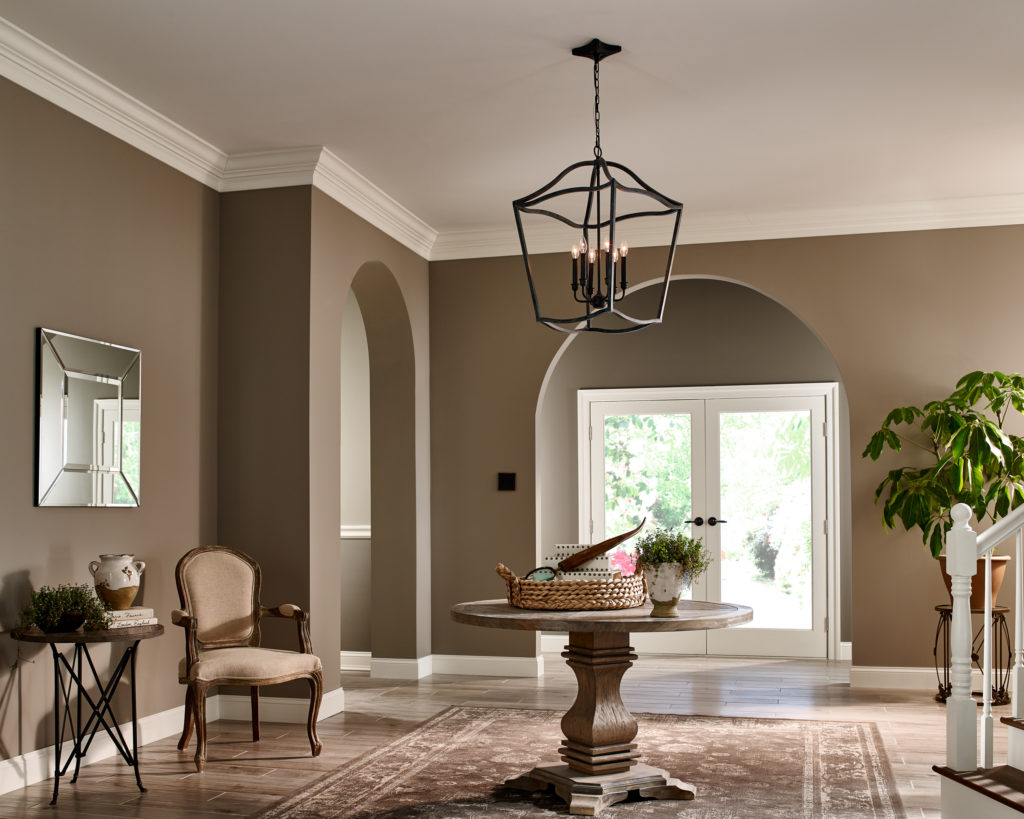 The wrought iron Yarmouth Cage Pendant hangs in a traditional-style foyer over a round wood table