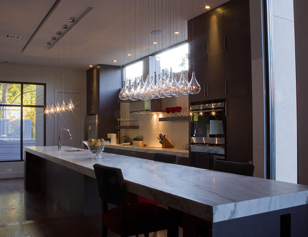 The 24-light Larmes Pendant is suspended over an extra-long marble kitchen island.