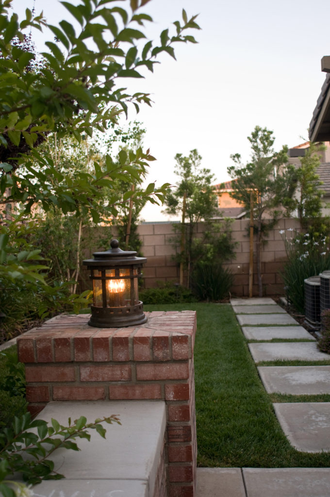 Outdoor lantern lights can be portable like the Santa Barbara lamp sitting on a brick ledge.