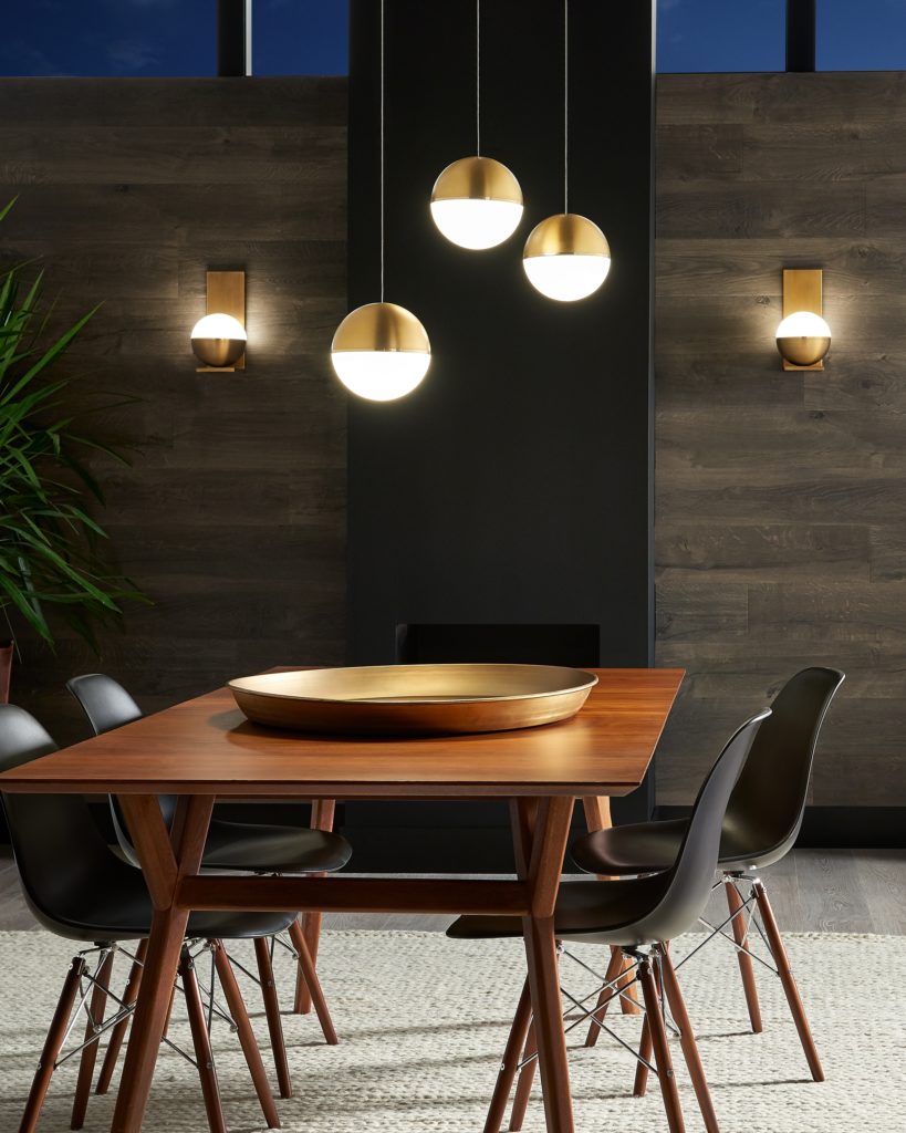Three round, brass-finished Akova mini-pendants complement a rectangular wood dining table.