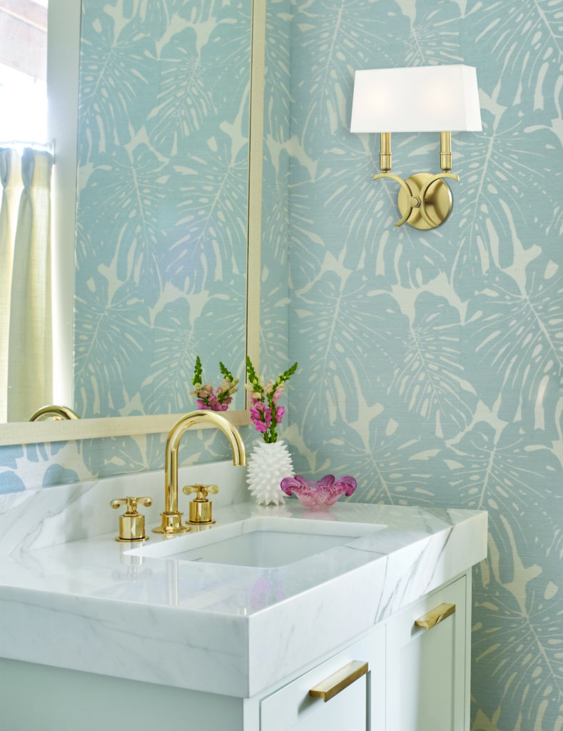 A Gwen wall sconce in a bathroom with light blue foliage wallpaper.