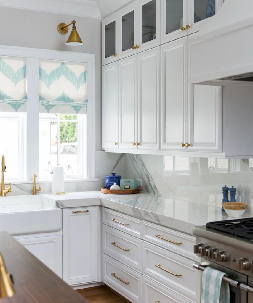 Bright white kitchen with gold hardware and marble countertops.