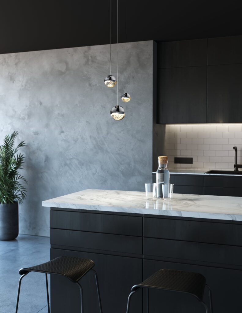 A bright kitchen with three white pendant lights hanging above a wooden countertop, complemented by light wooden cabinets.