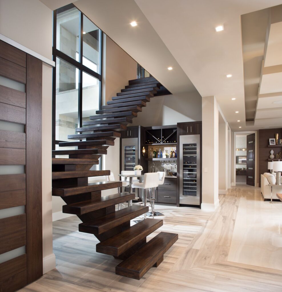A modern home entrance with a floating wooden staircase, a wet bar area, and large windows.