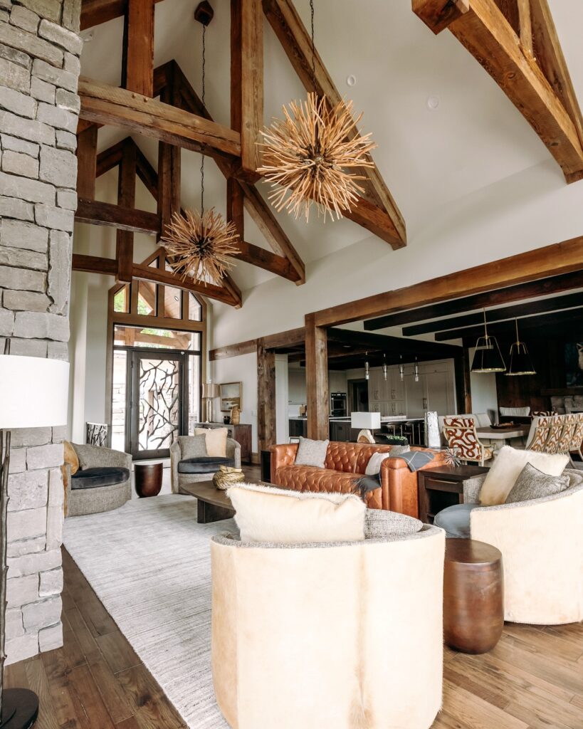 Spacious rustic living room with exposed wood beams, a stone fireplace, and unique sputnik-style chandeliers.