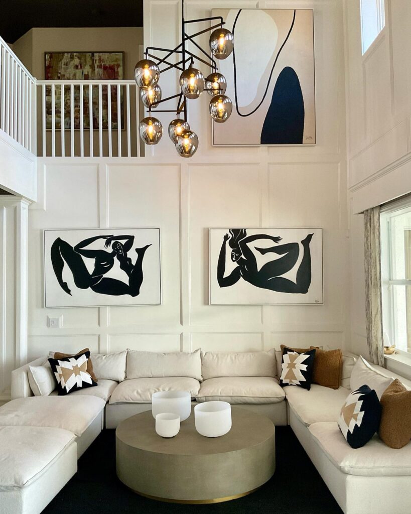 Modern living room with U-shaped sofa, abstract art, and large chandelier.