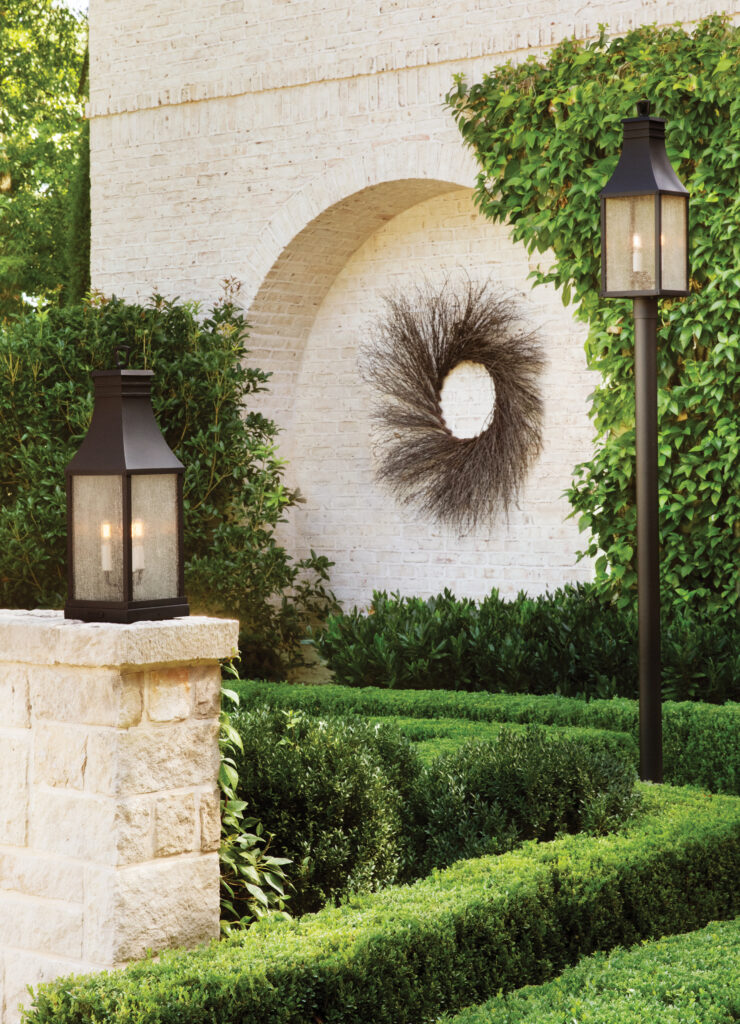 Traditional lantern post and pillar lights in a formal boxwood garden.