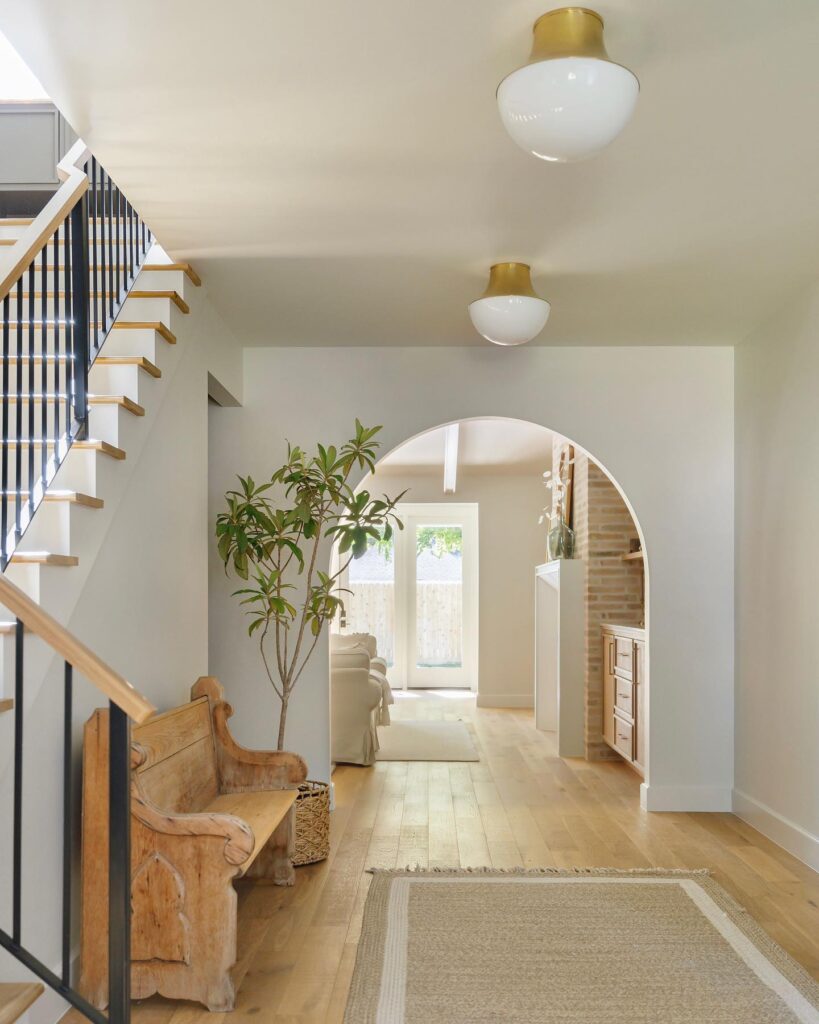 Hallway with wooden bench, arched doorway, and two Lettie Flush Mount lights.